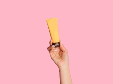 Eine Hand hält eine gelbe Tube vor einem gelben Hintergrund hoch | © Getty Images/Prostock-Studio