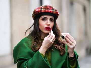 Streetstyle von Frau, die sich Lippenstift aufträgt | © Getty Images/Edward Berthelot 