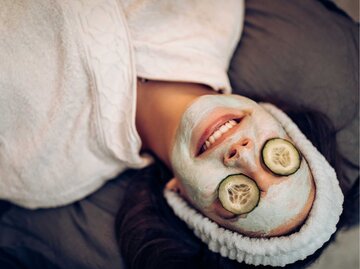 Frau im Bademantel, mit Quarkmaske und Gurkenscheiben auf den Augen | © Getty Images/StefaNikolic 