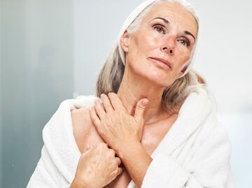 Eine Frau cremt ihren Hals und Nacken ein | © Getty Images / Westend61