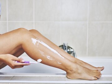 Nahaufnahme von Beinen einer Frau, die sie sich gerade rasiert | © Getty Images/Moyo Studio