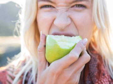 Frau beißt in einen Apfel | © Getty Images/Sam Diephuis