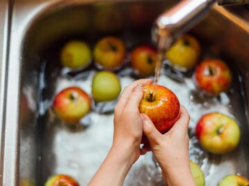 eine Hand am Waschbecken wäscht einen Apfel | © Getty Images/Westend61