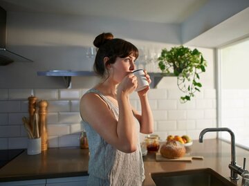 Frau trinkt Kaffee in der Küche | © Getty Images/Dougal Waters