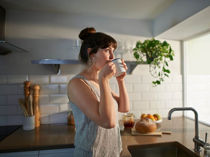 Frau trinkt Kaffee in der Küche | © Getty Images/Dougal Waters