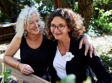 zwei Frauen Arm in Arm im Garten | © Getty Images/Oliver Rossi