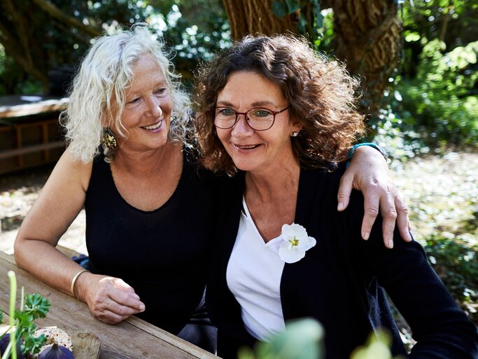 zwei Frauen Arm in Arm im Garten | © Getty Images/Oliver Rossi
