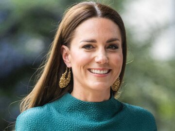 Prinzessin Kate trägt ein türkisfarbenes Kleid mit goldenen Ohrringen und lächelt | © Getty Images/Samir Hussein 