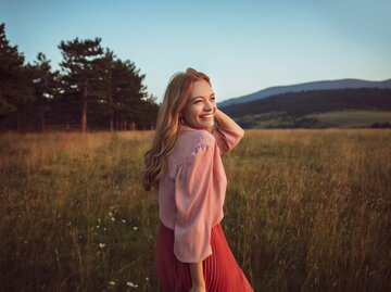 Glückliche Frau auf einem Feld | © Getty Images/Marko Geber