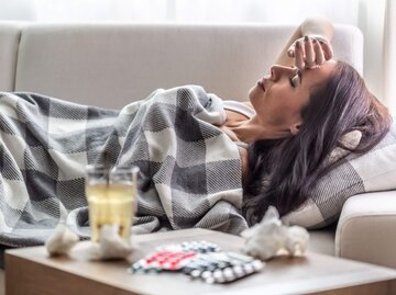 Frau liegt krank auf der Couch | © Getty Images/SimpleImages