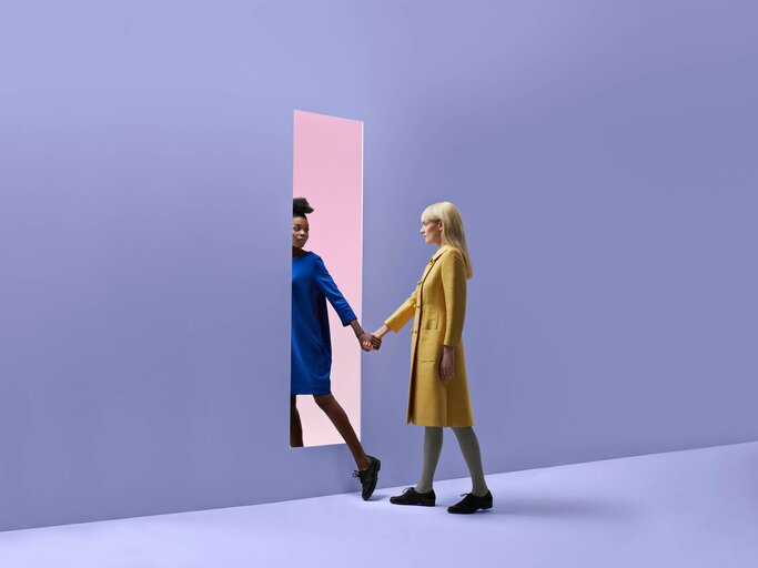 Zwei Freundinnen gehen gemeinsam durch eine Tür | © Getty Images/Klaus Vedfelt