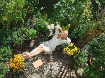 Eine Frau entspannt sich in mitten von einem schönen Garten | © GettyImages/Hans Huber