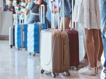 Passagiere mit Gepäck warten am Flughafen in der Schlange | © Getty Images/izusek