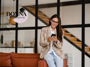  Frau sitzt entspannt auf dem Sofa im Büro und nutzt ihr Smartphone | © Adobestock/mary_markevich