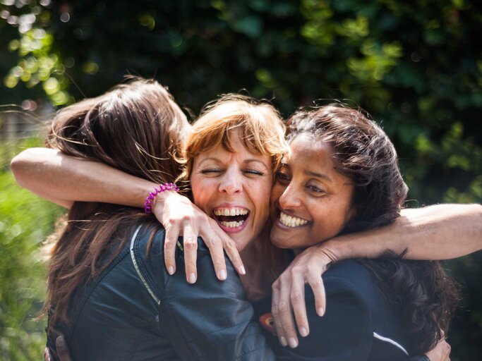 Drei erwachsene Frauen umarmen sich freudig | © Getty Images/Lucy Lambriex