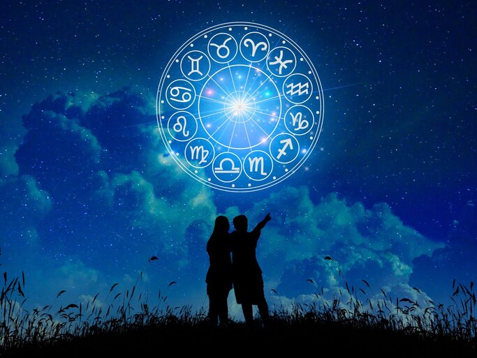 Personen umarmen sich und zeigen in Himmel mit Sternzeichenkreis | © Getty Images/sarayut Thaneerat
