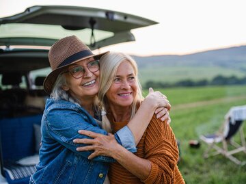 Zwei Personen umarmen sich vor Campingstuhl | © Getty Images/Halfpoint Images