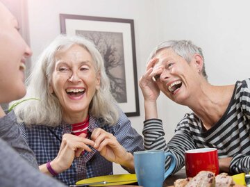 Ältere Frauen sitzen zusammen an einem Tisch und lachen  | © Getty Images/Betsie Van der Meer