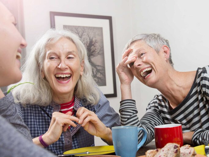 Ältere Frauen sitzen zusammen an einem Tisch und lachen  | © Getty Images/Betsie Van der Meer