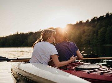 Glückliches Paar küsst sich auf einem Boot | © Getty Images/Guido Mieth