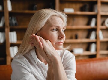 Frau mittleren Alters mit langen blonden Haaren hält sich die Hände an die Wange und macht ein besorgtes Gesicht. | © Getty Images / Inside Creative House