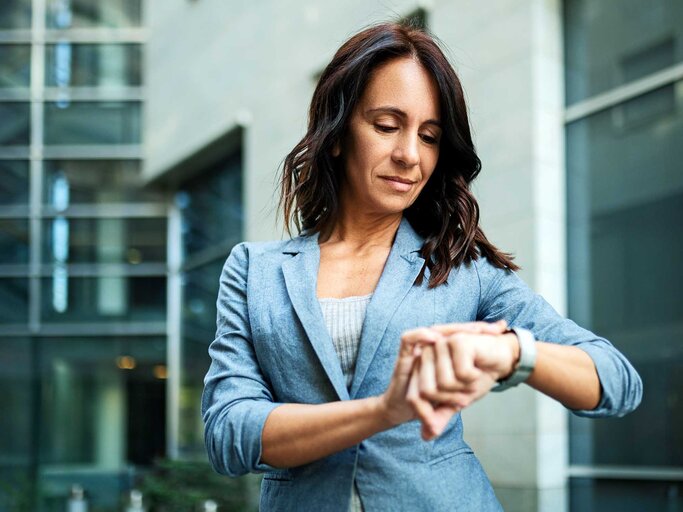 Frau im Business-Outfit schaut ungeduldig auf ihre Armbanduhr. | © Getty Images/Nastasic