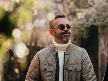 Ein Mann mit Bart trägt eine Sonnenbrille und lächelt | © GettyImages/Alina Rudya/Bell Collective