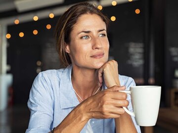 Frau hält eine Tasse Kaffee und schaut in die Ferne | © Adobe Stock/Rido
