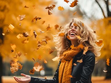 glückliche Frau im Herbslaub | © Adobe Stock/Gautierbzh