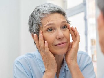 Frau schaut in den Spiegel und macht Face Yoga | © Getty Images/Ridofranz