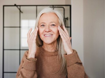 Frau mit grauen Haaren fasst sich ins Gesicht | © Getty Images/Westend61