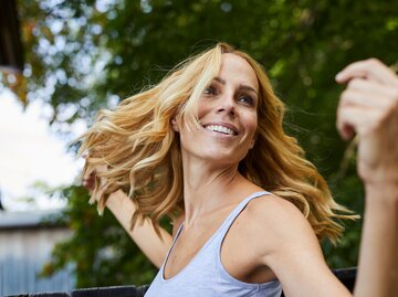 Eine Frau hat strahlend schöne Haare und dreht sich lachend | © GettyImages/Westend61