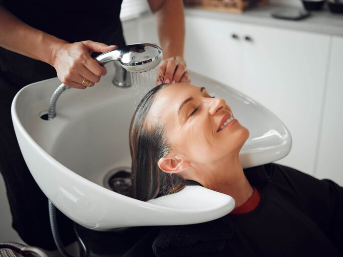 Person lässt sich bei Friseur Haare waschen | © Getty Images/PeopleImages