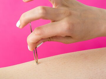 Frauenhand zupft mit Pinzette ein Haar aus | © Getty Images/Creative-Family