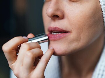 Nahaufnahme einer Frau, die Lippenstift aufträgt | © Getty Images/miniseries