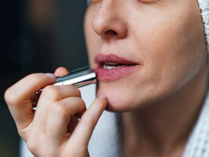 Nahaufnahme einer Frau, die Lippenstift aufträgt | © Getty Images/miniseries