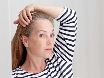 Frau betrachtet ihre grauen Haare im Spiegel | © Getty Images/Tatiana Foxy