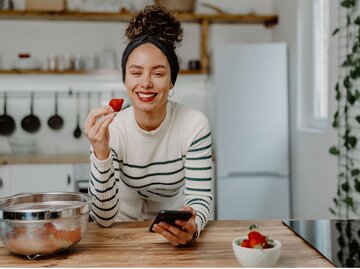 Eine Frau mit strahlendweißem Lächeln isst Erdbeeren  | © Getty Images / milan2099