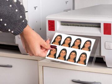 Person nimmt Passfotos aus Drucker | © Getty Images/Photology1971