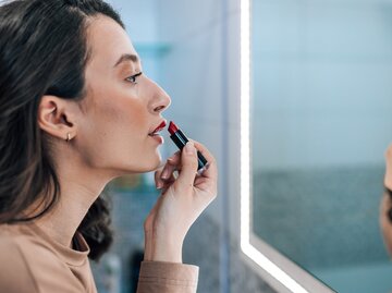 Frau trägt sich roten Lippenstift auf | © GettyImages/RealPeopleGroup