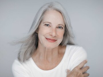 Frau mit grauen Haaren sieht jung aus und lächelt in die Kamera. | © Adobe Stock/Kanea
