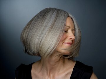 Eine Frau dreht den Kopf zur Seite und präsentiert ihre schönen grauen Haare | © GettyImages/Ralf Nau