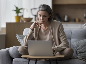 Eine Frau sitzt nachdenklich vor ihrem Laptop | © GettyImages/fizkes