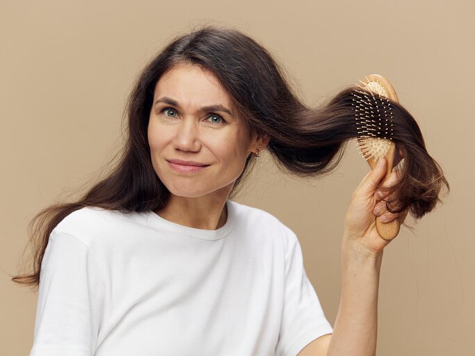 Frau kämmt ihr braunes Haar | © AdobeStock/Tatiana