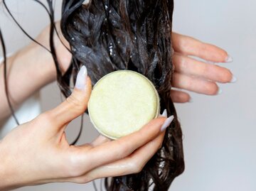 Nahaufnahme von nassen Haarsträhnen mit einem Stück Shampoo  | © Getty Images / Lourdes Balduque