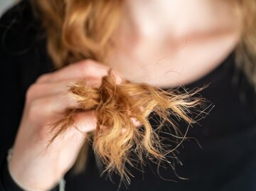 Frau hält trockene Haarspitzen zwischen den Fingern | © AdobeStock/Sonja Rachbauer