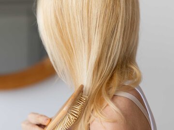 Blonde Frau bürstet sich die Haare | © Adobe Stock/Prostock-studio