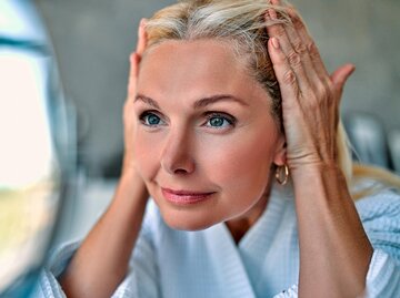 Reife Frau fasst sich mit den Händen ins blonde Haar | © AdobeStock/Vasyl
