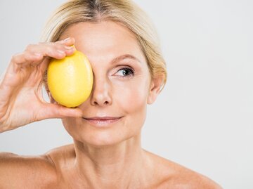 Eine Frau hält sich eine Zitrone vor ein Auge | © GettyImages/LightFieldStudios