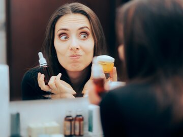 Eine Frau macht ein komisches Gesicht und schaut in den Spiegel | © GettyImages/nicoletaionescu